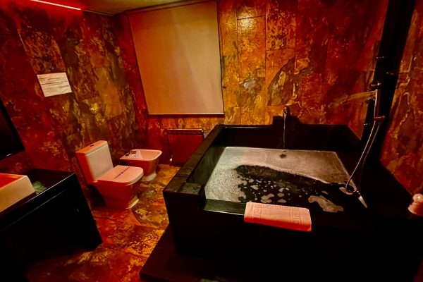 Bañera de jacuzzi de mármol negro con iluminación roja en suite romántica en Madrid